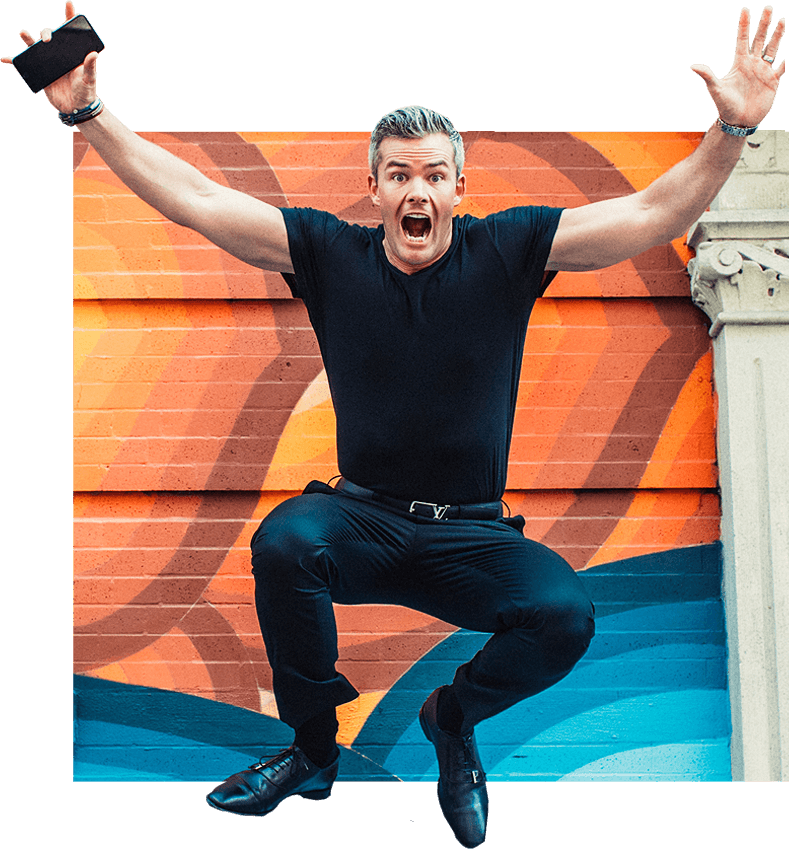 Ryan Serhant jumping in the air against a colorful mural backdrop.